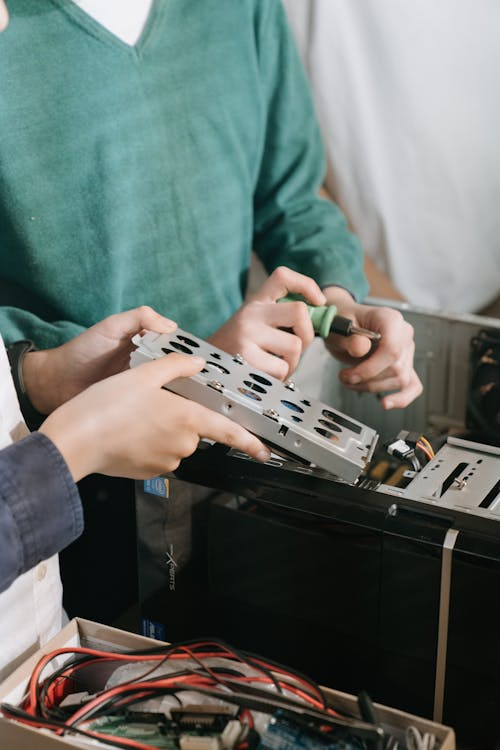 Two technicians inspecting the internal hardware components of a desktop PC during diagnostics